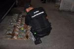 Na ziemi przed funkcjonariuszem ułożone paczki z marihuaną, przed paczkami klęczy umundurowany funkcjonariusz.