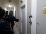 Na korytarzu funkcjonariusze stoją przed drzwiami.