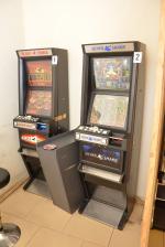 Wewnątrz pomieszczenia stoją pod ścianą dwa włączone automaty do gier.