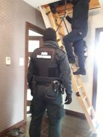 Jeden z funkcjonariuszy wchodzi po drabinie na poddasze.