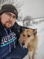 Mężczyzna z psem. W tle ośnieżony krajobraz.