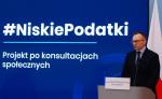 Wiceminister Finansów Artu Soboń stoi na tle planszy z napisem #NiskiePodatki - projekt po konsultacjach społecznych
