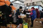 na dworcu dużo ludzi z Ukrainy, namiot, kartony z żywnością, funkcjonariuszka służby celno-skarbowej trzyma karton z kanapkami