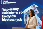na tle planszy z napisem: wspieramy Polaków w spłacie kredytów hipotecznych, stoi minister finansów Magdalena Rzeczkowska