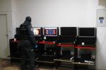 Funkcjonariusz Służby Celno-Skarbowej stoi przed 5 stanowiskami komputerowymi, na których są zainstalowane nielegalne gry hazardowe.