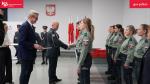 poczas uroczystości naczelnk LUCS ściska dłoń nowemu funkcjonariuszowi, dyrektor wręcza akty mianowania do służby, w tle flaga i godło Polski