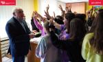 Urzędnik stoi naprzeciwko dzieci podnoszą ręce w geście zgłaszania się