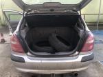 Otwarty bagażnik srebrnego Nissana Almera hatchback z dwoma zapasowymi oponami, brak widocznych uszkodzeń pojazdu, widoczne ślady użytkowania