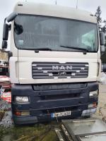 Przód samochodu ciężarowego MAN TGA 26.354 . Górna część kabiny biała, dolna część kabiny zderzak grill  grafitowa. Dwa lusterka boczne  po obu stronach kabiny w kolorze czarnym. Na środku grilla widoczny duży napis MAN . Grill składa się z kilku poziomych segmentów w kolorze ciemnej szarości. Górna sekcja- reflektory główne w formie prostokątnych modułów. Dolna sekcja kierunkowskazy i dodatkowe światła.