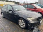 Czarne BMW 318 nadwozie typu sedan, ujęcie prawego przodu, felgi stalowe z plastikowymi kołpakami w kolorze srebrnym, lusterka w kolorze nadwozia, przyciemniane tylne szyby; 