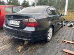 Czarne BMW 318 nadwozie typu sedan, ujęcie prawego tyłu, felgi stalowe z plastikowymi kołpakami w kolorze srebrnym, lusterka w kolorze nadwozia, przyciemniane tylne szyby.