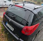 Tył czarnego Peugeot 207 kombi ze srebrnymi relingami, antena, szyby tylne przyciemniane, nieznacznie przerysowany tylni zderzak