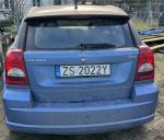 Tył niebieskiego Dodge Caliber, hatchback, widoczne wgniecenie oraz liczne zarysowania lakieru 