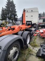 prawa strona  samochodu ciężarowego marki MAN TGA   koloru białego . Lusterka boczne koloru czarnego. Rama i mechanizm hakowy w kolorze pomarańczowym z licznymi miejscami rdzy. Nadkola w kolorze czarnym. Koła stalowe w kolorze chrom . ogumienie  w stanie dobrym. Widoczne zbiorniki paliwa