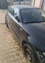 prawy bok czarnego BMW 116i z widocznymi zarysowaniami oraz uszkodzonym zderzakiem