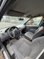 Ciemnoszara Dacia Logan, ujęcie wnętrza pojazdu, ciemnoszara tapicerka welurowa z elementami w kolorze szary i czarny w pepitkę, przetarcie na siedzisku kierowcy, manualna skrzynia biegów, radioodtwarzacz CD 1 DIN, elektroniczne sterowane szyby i lusterka, klimatyzacja manualna